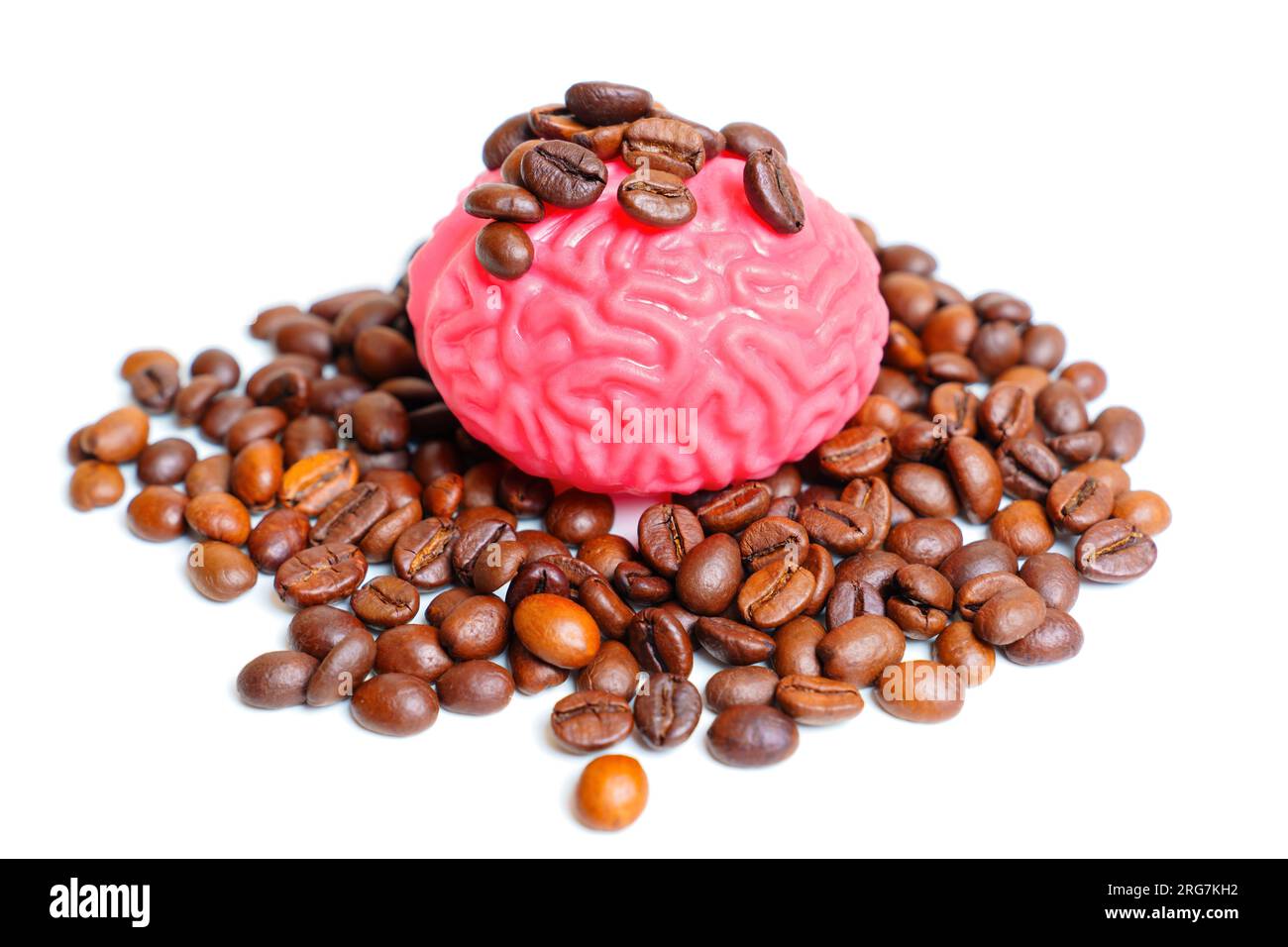 Rosafarbenes, gelee ähnliches menschliches Gehirnmodell in einem Haufen gerösteter Kaffeebohnen, isoliert auf weißem Hintergrund. Kaffee als mentale Leistungssteigerung und Stockfoto
