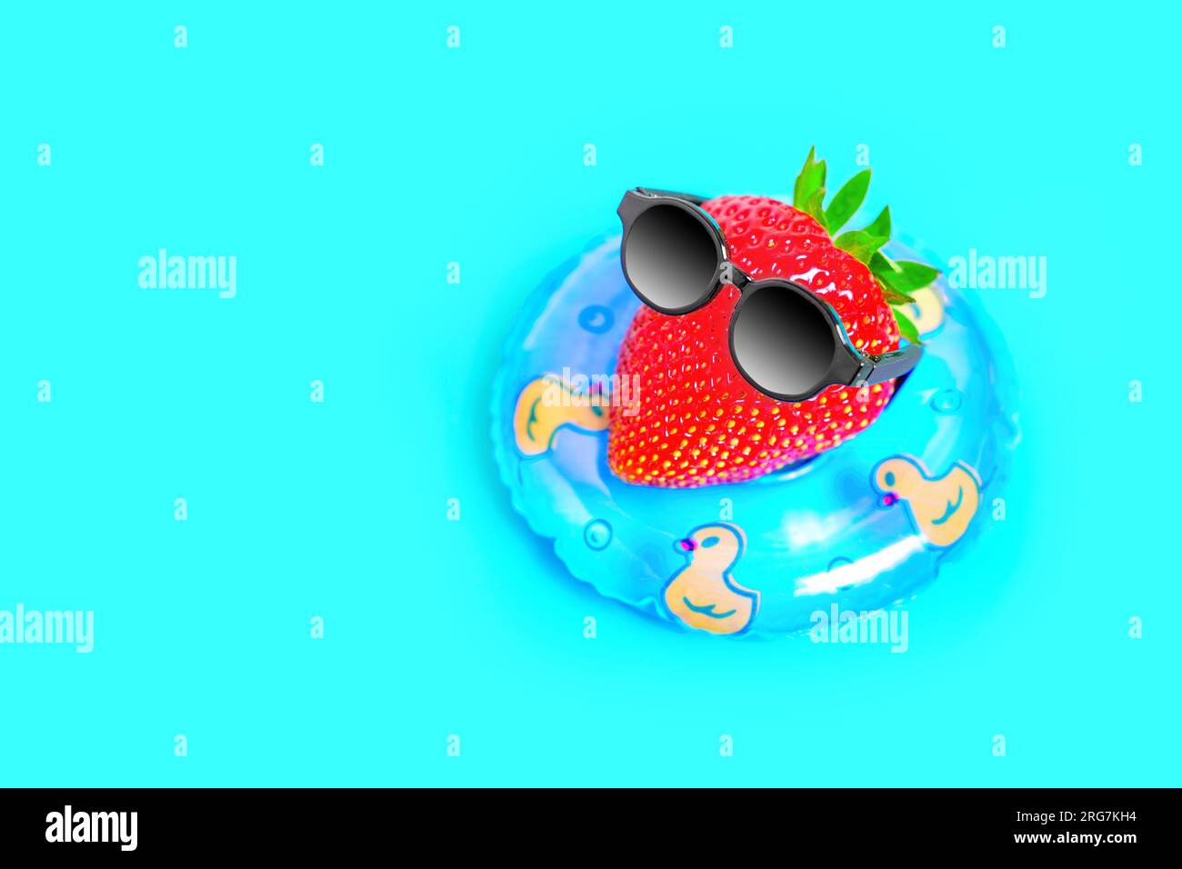 Charmante Figur aus einer frischen, saftigen Erdbeere mit schwarzer Sonnenbrille, schwimmt auf einer aufblasbaren Tube im Pool. Lebhaftes heißes Sommerrefugium Stockfoto