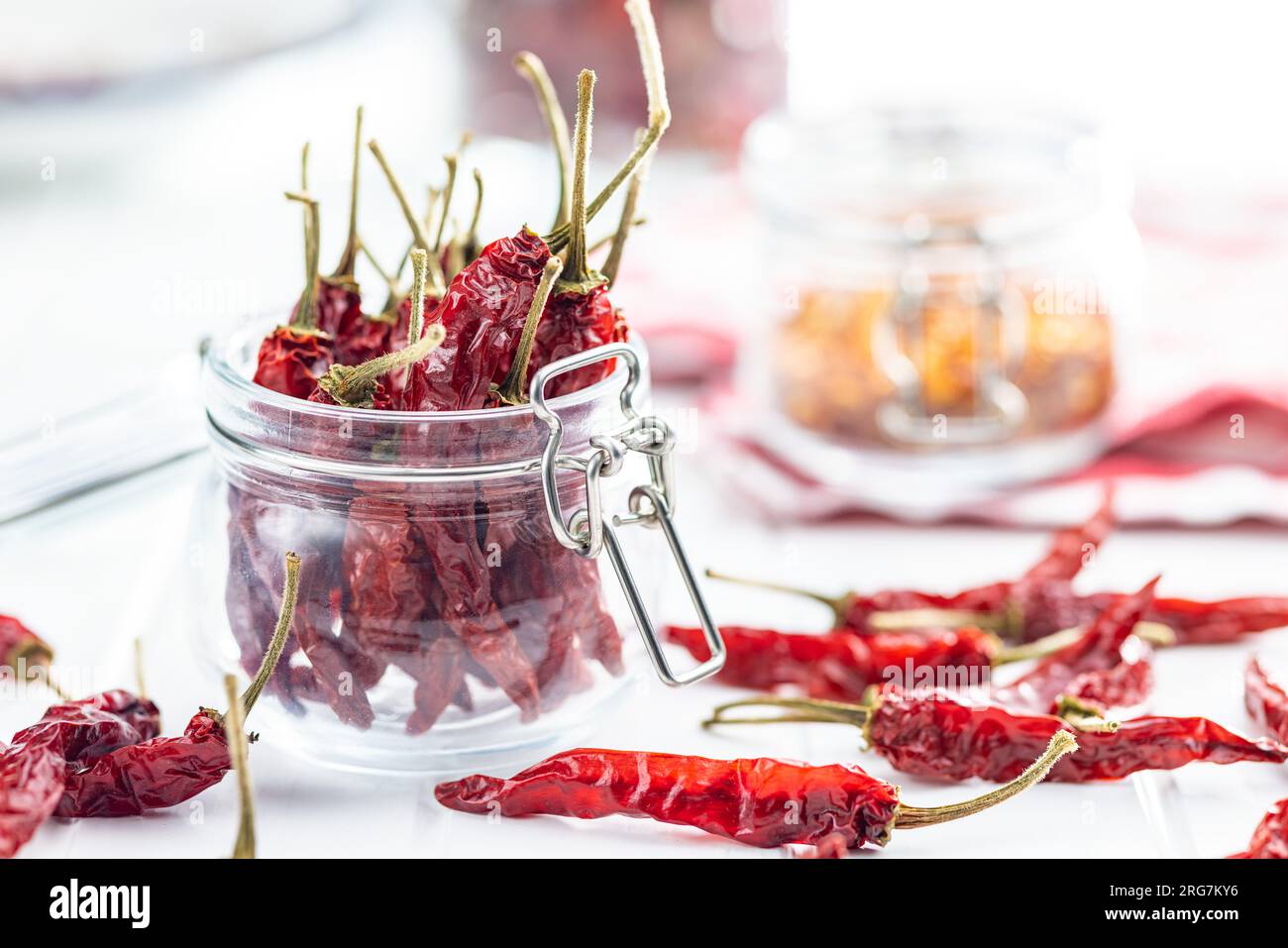 Rote Chili-Paprika im Glas auf dem weißen Tisch. Stockfoto