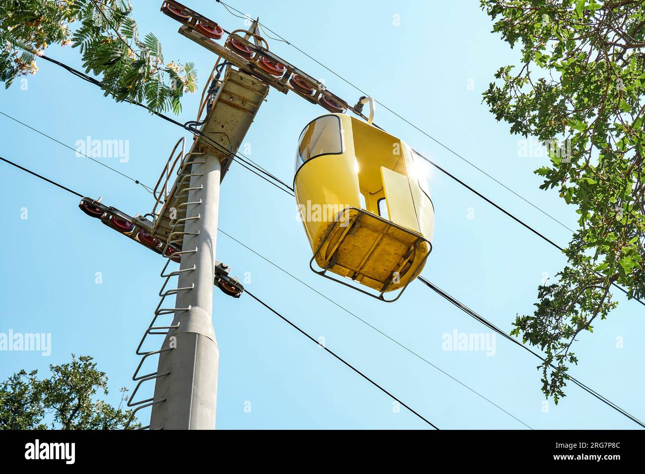 Gelbe Kabine der Seilbahn vor dem sonnenbeleuchteten blauen Himmel. Touristenattraktion im Vergnügungspark für ankommende Besucher im Resort Stockfoto