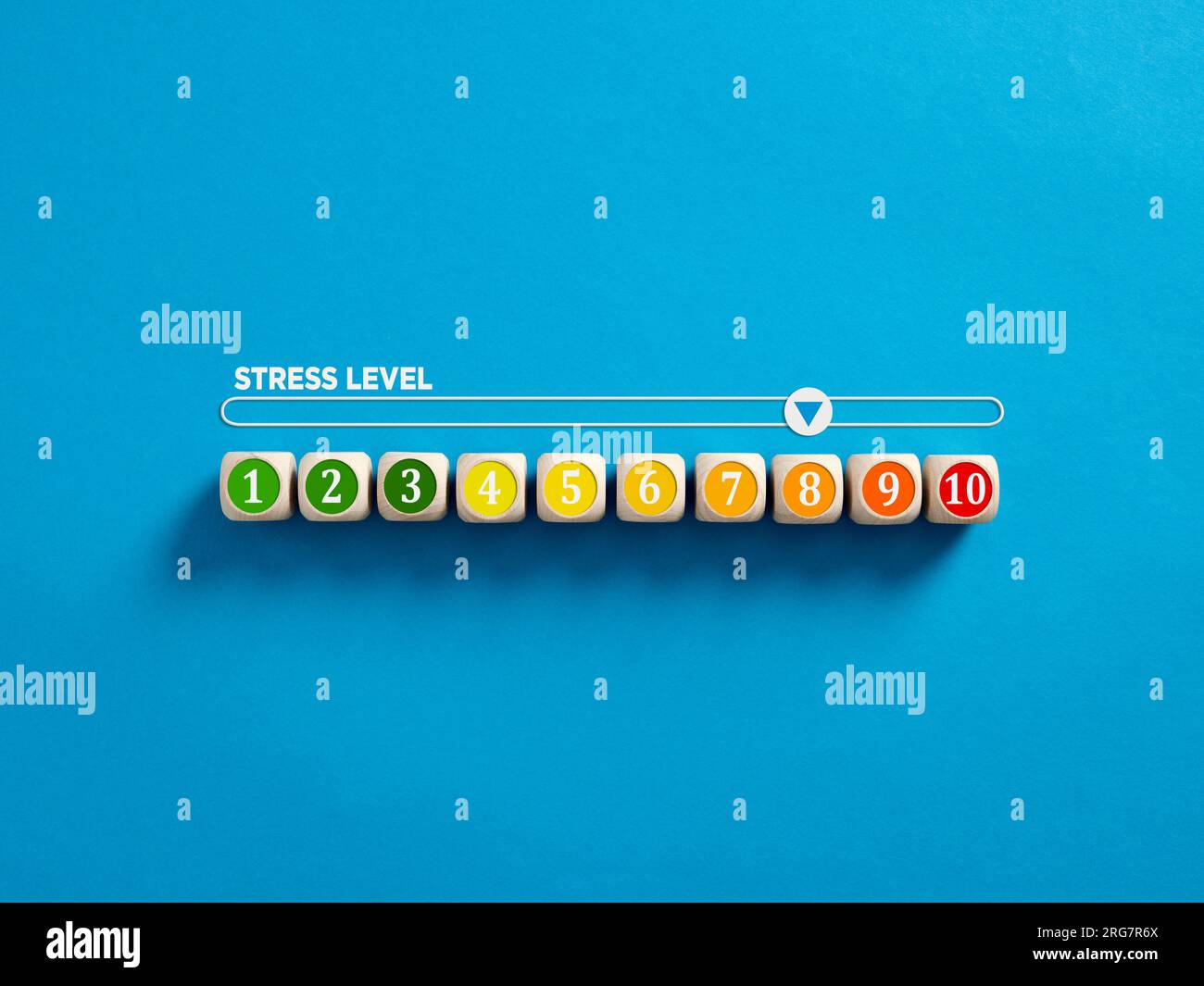 Indikator zur Messung des Stressniveaus. Hoher Stresslevel. Stresspegel-Nummern auf Holzwürfeln mit einem Stressmesser auf blauem Hintergrund. Stockfoto