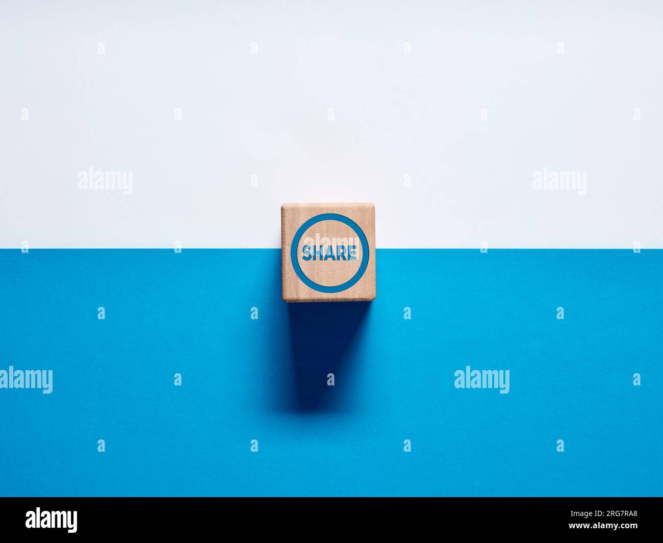Das Wort Share on Wood Cube (auf Holzwürfel teilen) auf blauem und weißem Hintergrund. Share-Taste. Stockfoto