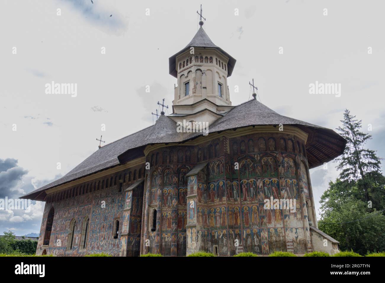 Wunderschöne Fassade eines bemalten orthodoxen Klosters in Rumänien mit dramatischem Himmelshintergrund Stockfoto