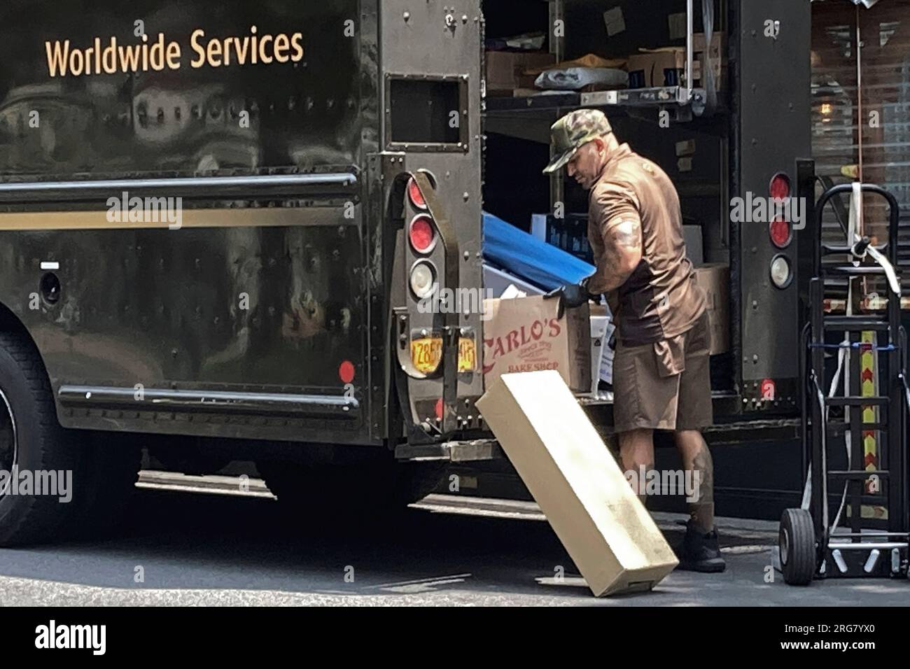 File - A United Parcel Service driver sorts his deliveries, on New York's Upper West Side, Saturday, July 15, 2023. Higher pay is one issue driving strikes among Hollywood writers and actors, and was a focus on the Teamsters union in their negotiations with UPS, which led to large pay gains. (AP Photo/Richard Drew, File) Stockfoto