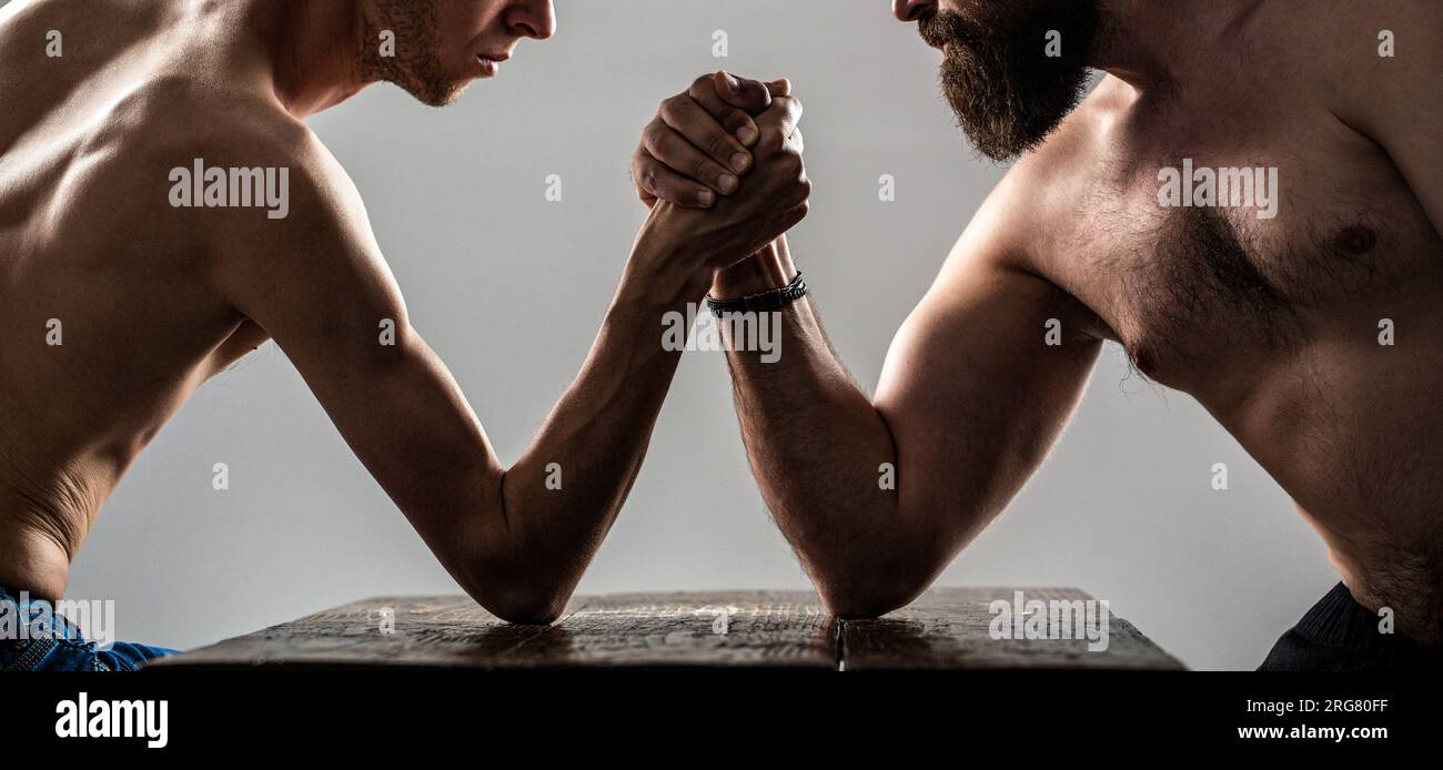 Arme ringen dünne Hand, großer starker Arm im Studio. Zwei Männerhände umklammten Arm Wrestling, stark und schwach, ungleiche Übereinstimmung. Stark muskulös bärtiger Mann Stockfoto