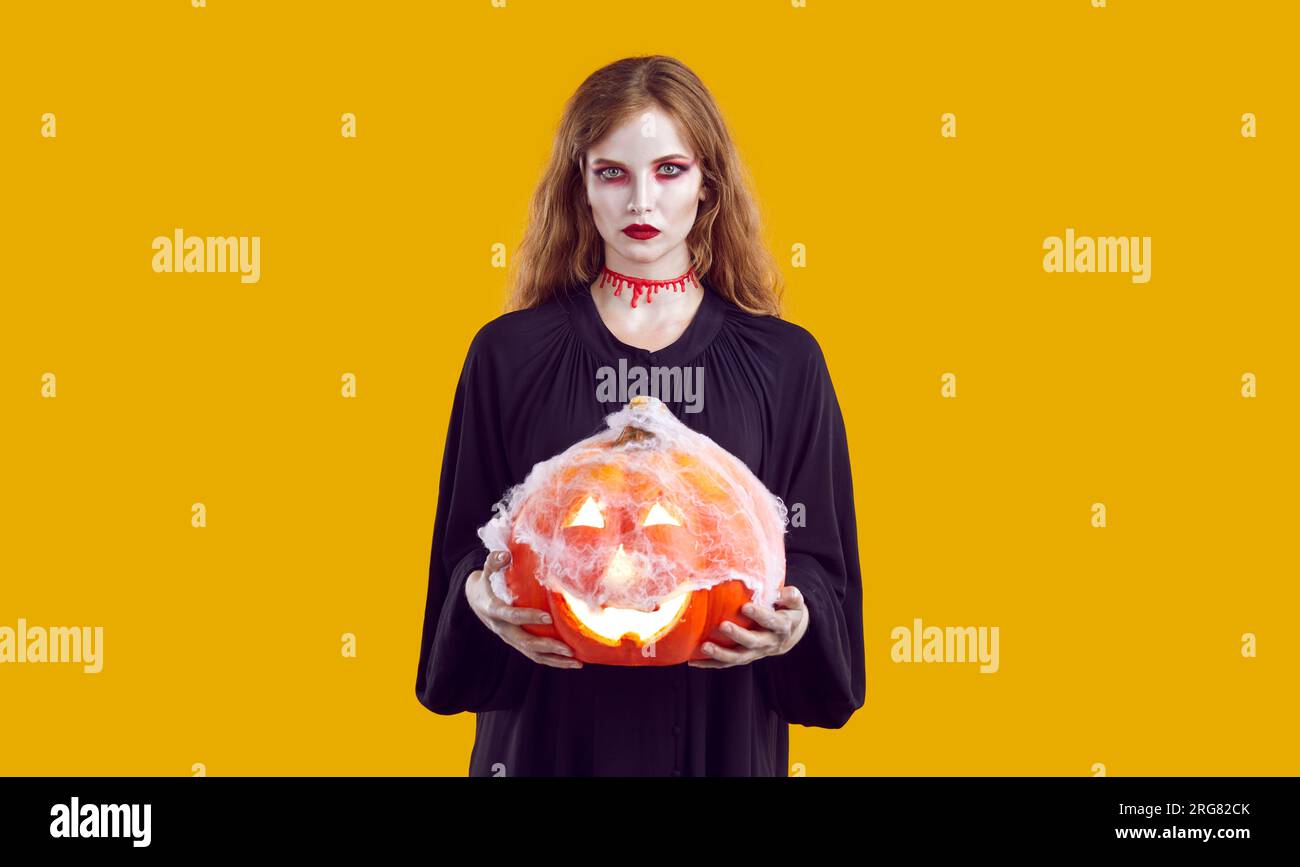 Eine Frau im gruseligen Halloween-Kostüm, mit Blut am Hals und Jack o Laterne in den Händen Stockfoto