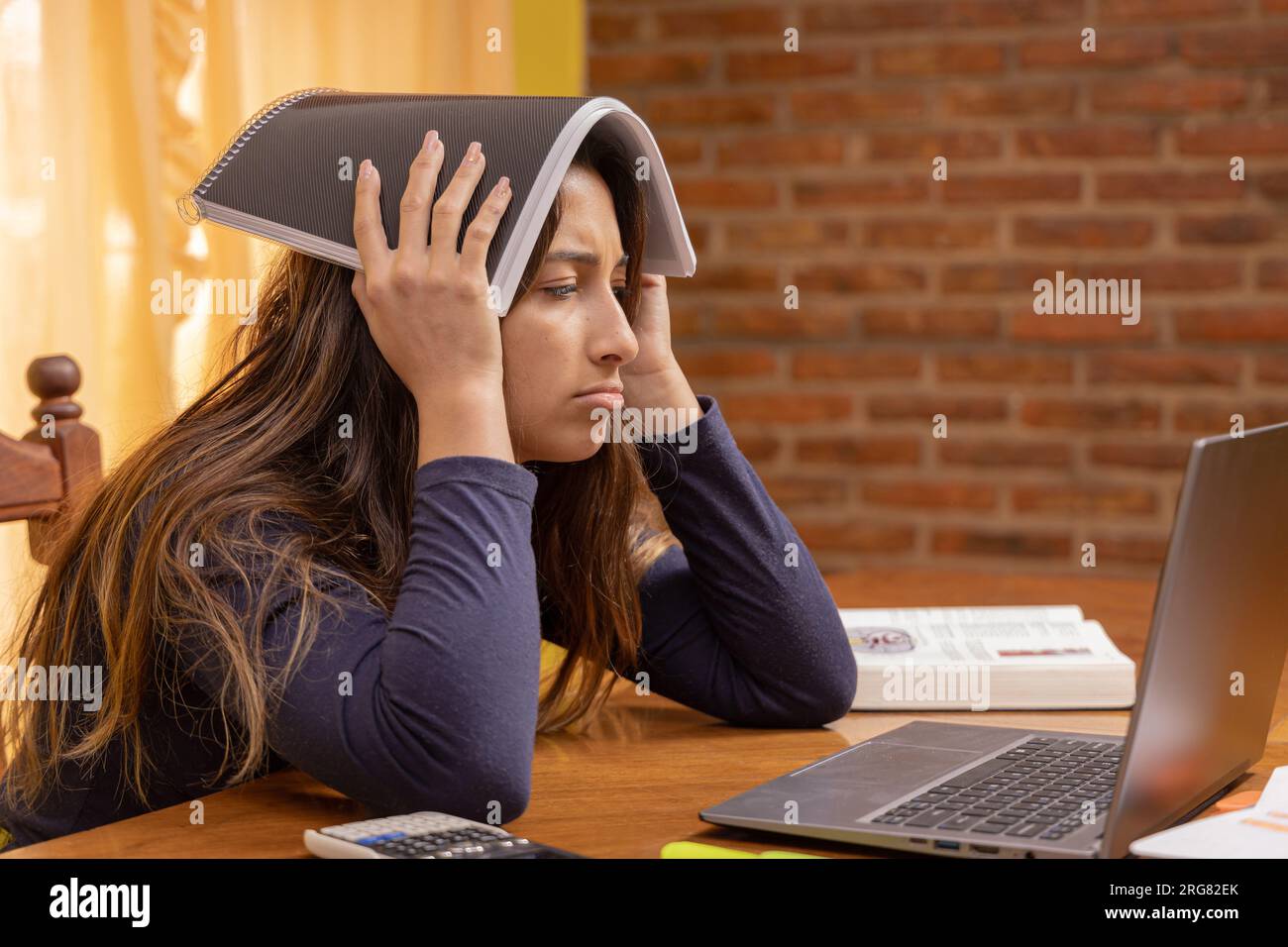 Erschöpftes Latina-Mädchen, das vor einem Laptop lernt. Stockfoto