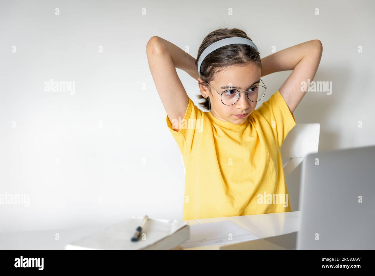Süßes Schulmädchen mit einem Laptop, das zu Hause lernt, online lernt. Stockfoto