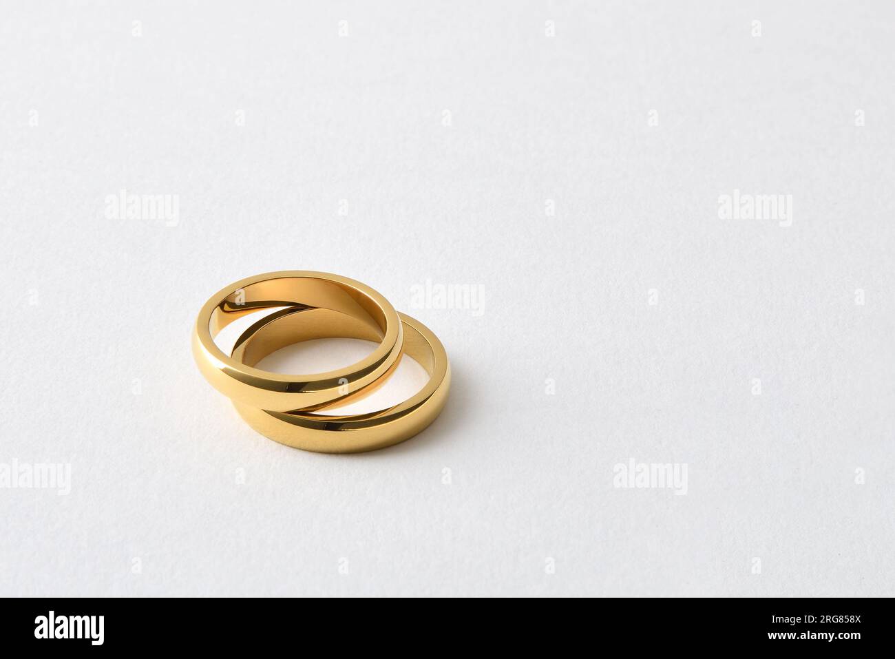 Detail von zwei goldenen Eheringen, die einen übereinander liegen, auf weißem, isoliertem Hintergrund. Erhöhte Aussicht. Stockfoto