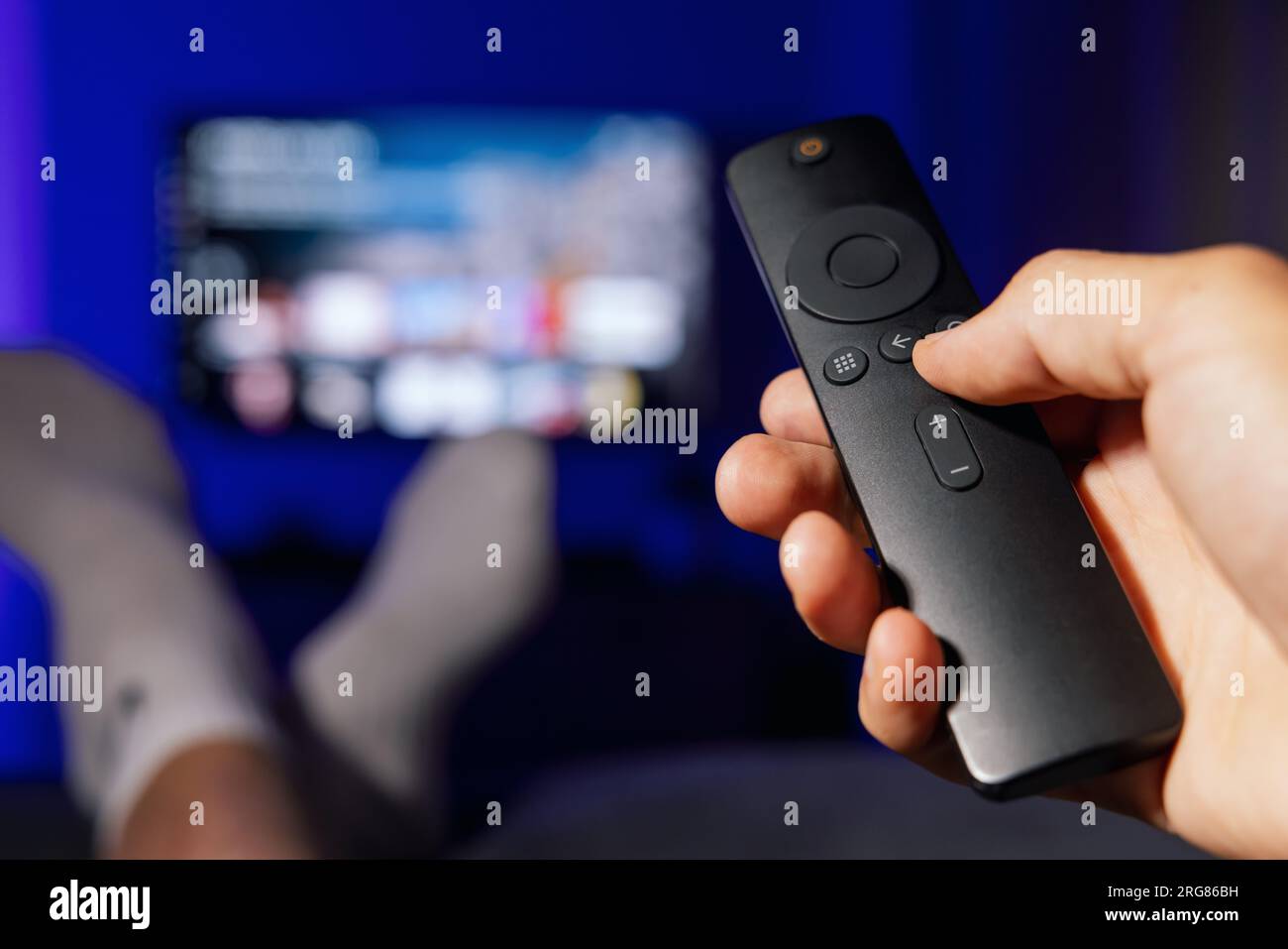 Hand mit tv-Fernbedienung. Mann, der zu Hause Inhalte von Streaming-Diensten ansieht Stockfoto