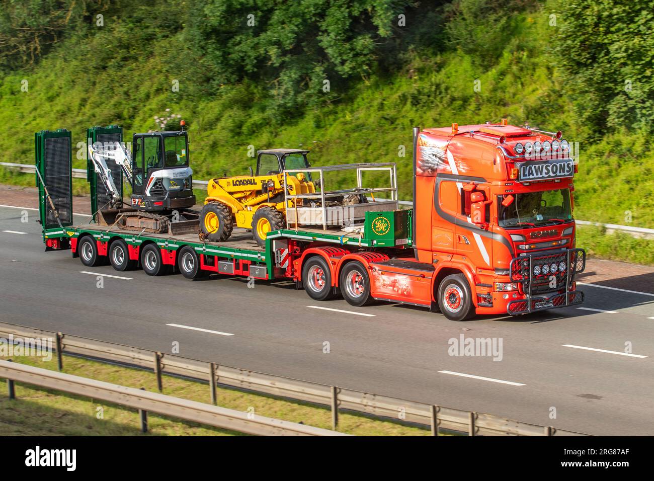 Lawsons Haulage Ltd., Speditionsunternehmen in Cockermouth, mit nicht ausfahrbarem Flachlader, Stufenrahmen für Stadtfahrzeuganhänger sowie Werksmaschinen. 2010 Diesel 6353 cm3 Red Scania Traktoreinheit, fährt auf der Autobahn M6 in Greater Manchester, Großbritannien Stockfoto