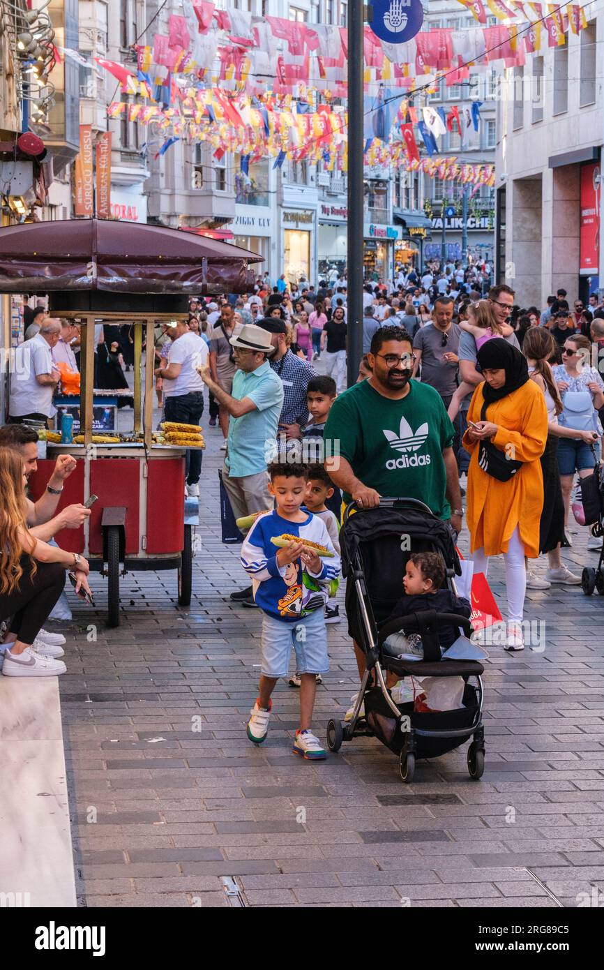 Istanbul, Türkei, Türkiye. Istiklal Street, Familie kauft gerösteten Mais für Kinder. Stockfoto