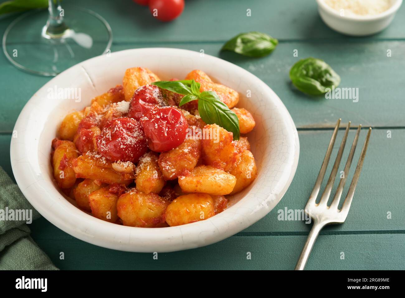 Kartoffelgnocchi. Traditionelle hausgemachte Kartoffelgnocchi mit Tomatensoße, Basilikum und Parmesan auf türkisfarbenem rustikalem Küchentisch. Traditi Stockfoto