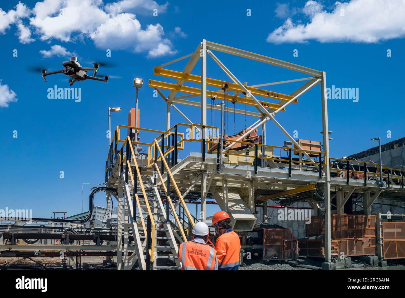Drohnenbediener mit Fernbedienung für eine thermische UAV-Kamera, Vermessung einer Baustelle, in einem Industriegebiet, Drohneninspektion junger Bergbauarbeiter Stockfoto