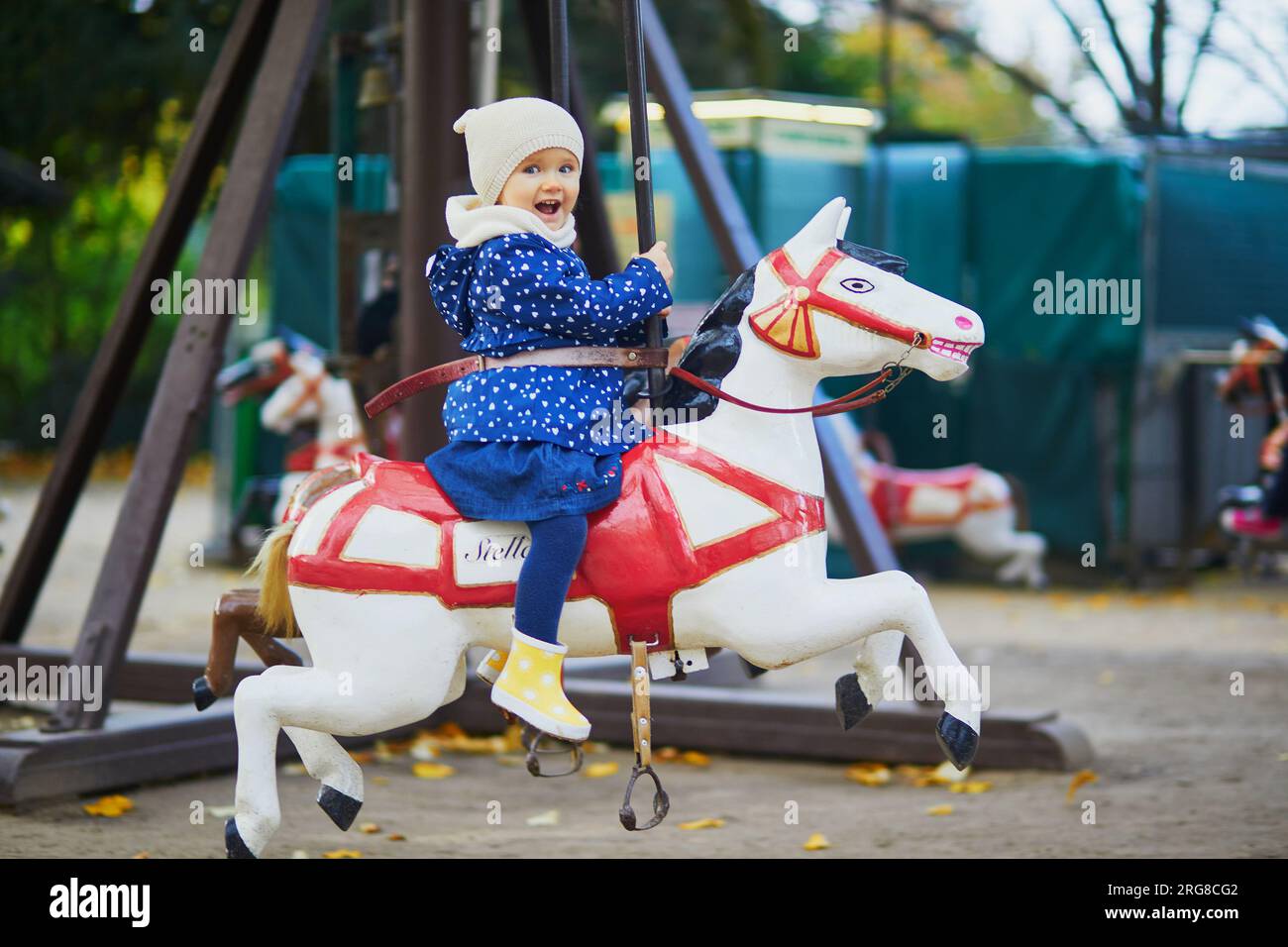 Ihr Kind hat Spaß auf einem alten französischen Karussell in Paris. Ein bezauberndes kleines Mädchen auf dem Spielplatz. Aktivitäten im Freien für kleine Kinder Stockfoto