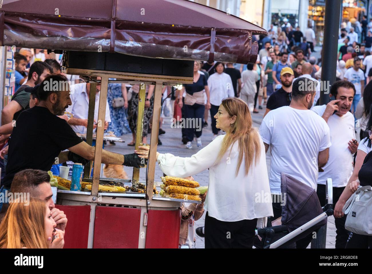 Istanbul, Türkei, Türkiye. Istiklal Street, Verkäufer, der eine Tüte gerösteter Kastanien an einen Kunden verkauft. Stockfoto