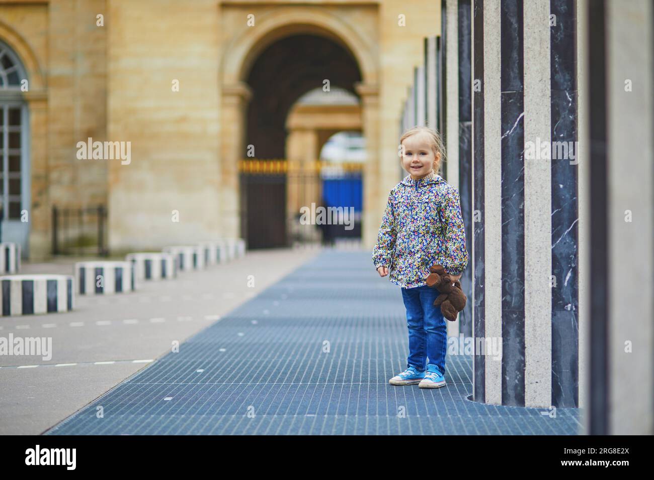 Fröhliches, fröhliches Kleinkind, das in den Säulen von Buren im Palais-Royale, Paris, Frankreich, läuft Stockfoto