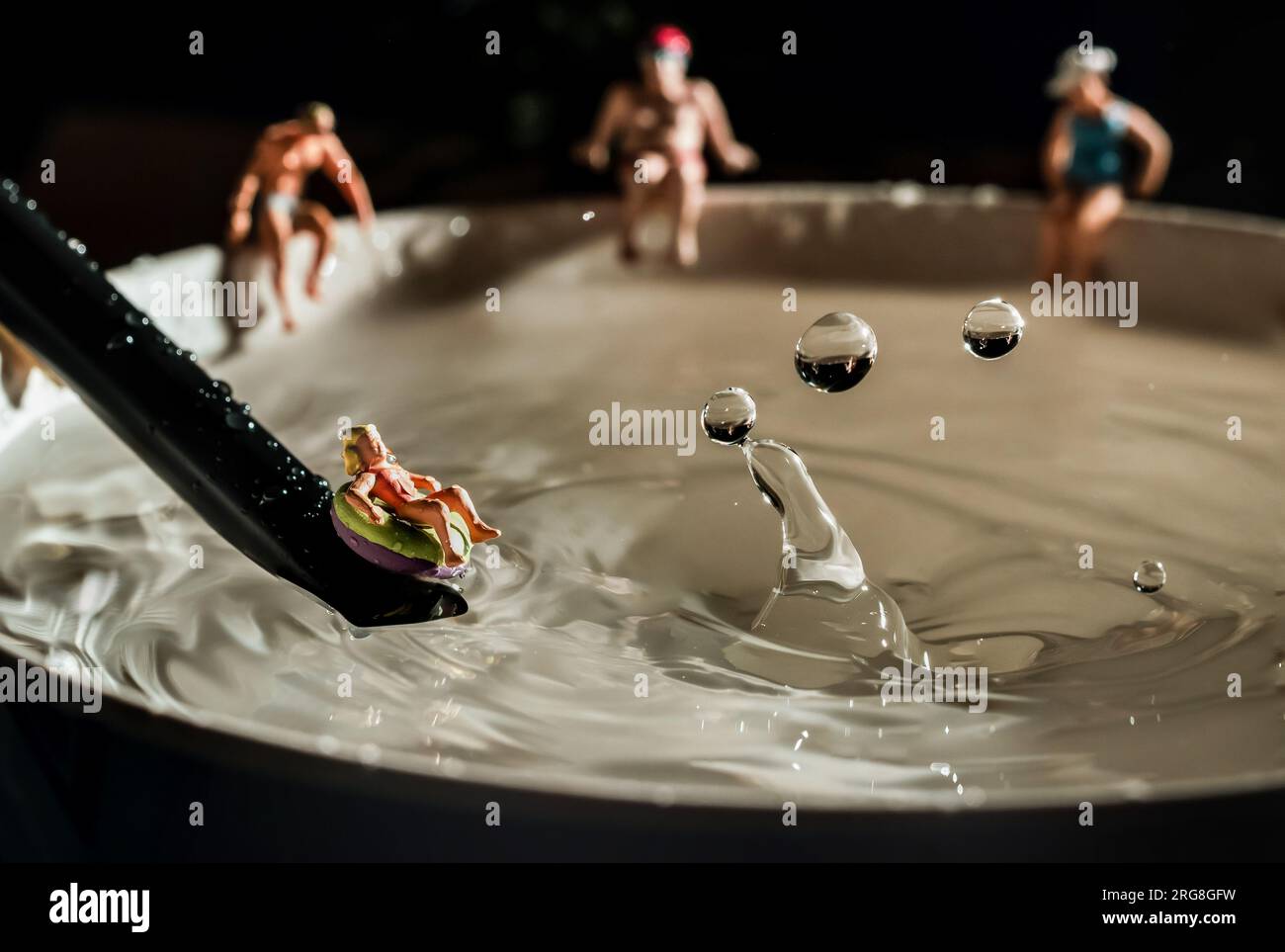 Wasserpark-Konzept Miniaturfiguren rutschen und planschen in einen Wasserpool Stockfoto