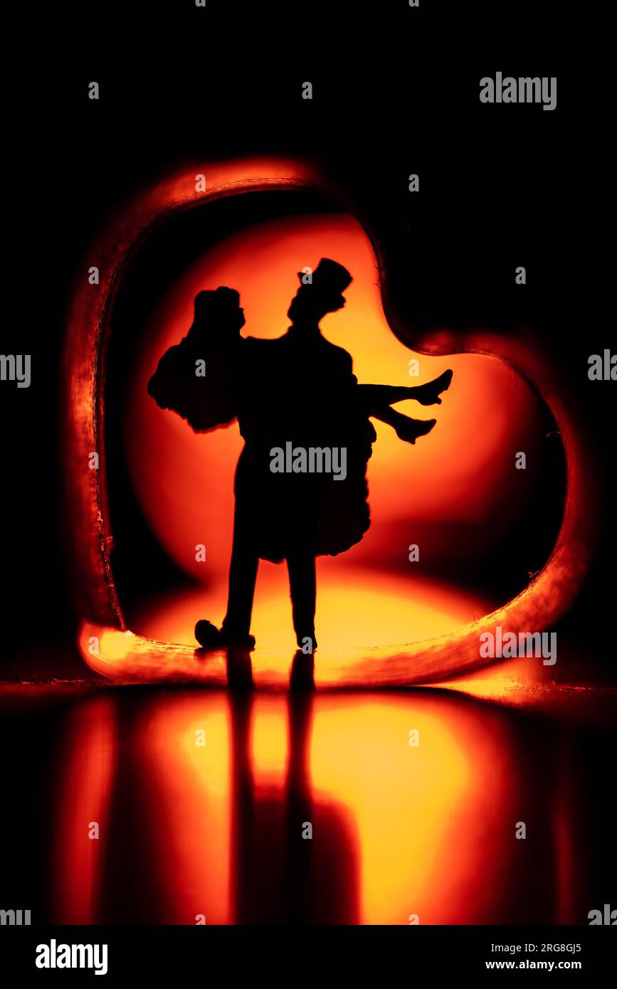 Gerade verheiratetes Concept-Miniaturpaar der Mann trägt seine frisch verheiratete Frau über eine herzförmige Türschwelle Stockfoto