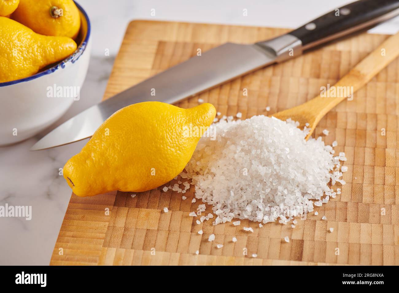 Zitrone und Haufen grobes Meersalz auf dem Schneidebrett Stockfoto
