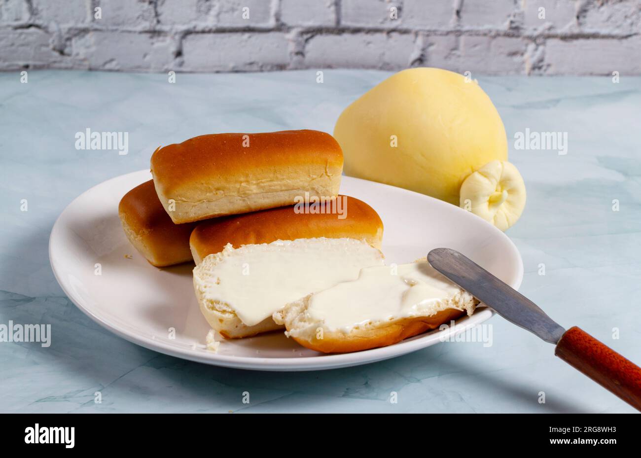Einige Brötchen in Brasilien werden als „Bisnaguinha“ bezeichnet, gefüllt mit Käse und Frischkäse auf einem weißen Teller. Stockfoto