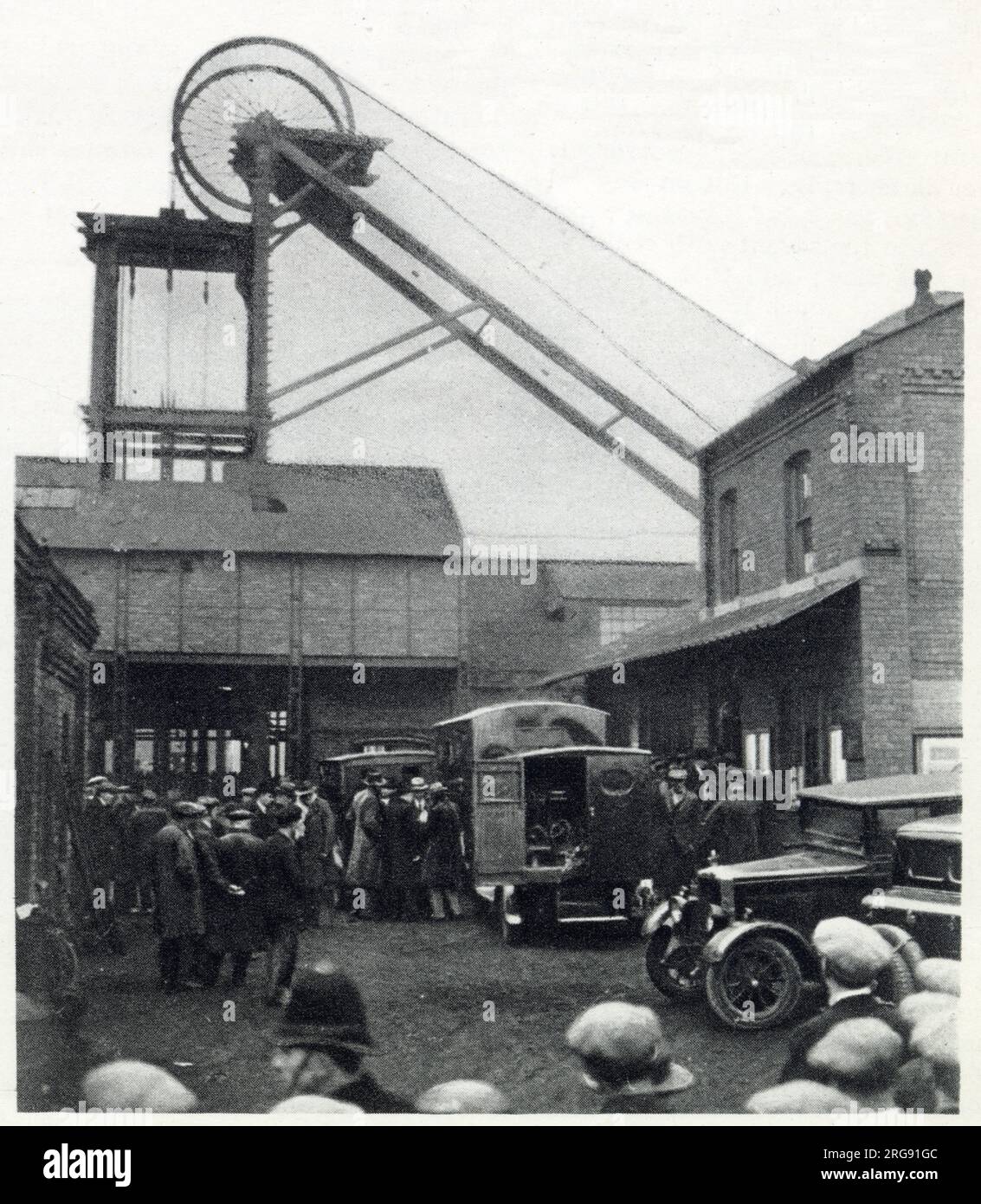 Bickershaw Colliery in Lancashire, wo sich am 10. Oktober 1932 eine Kohlebergwerkskatastrophe ereignete. Ein Aufzug mit 20 Leuten fiel auf die Mine und tötete alle bis auf eine Person. Szene am Boxenkopf nach der Explosion in der Mine, Gruppe ängstlicher Menschen, mit Krankenwagen in Bereitschaft. Stockfoto