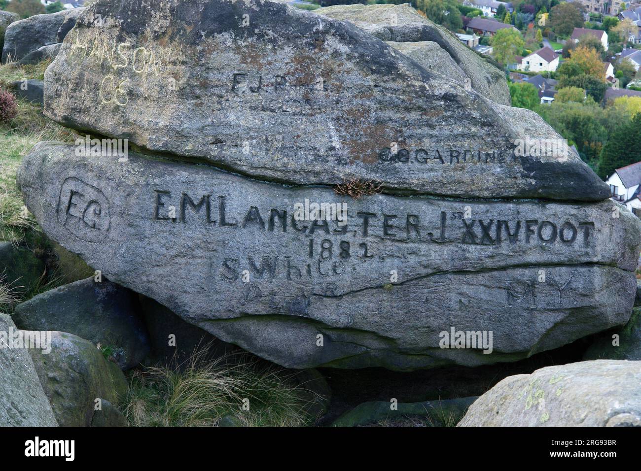 Namen auf Felsen gemeißelt in Ilkley Moor, West Yorkshire. Der prominenteste Name ist E M Lancaster, 1. XXIV Fuß, 1882. Stockfoto