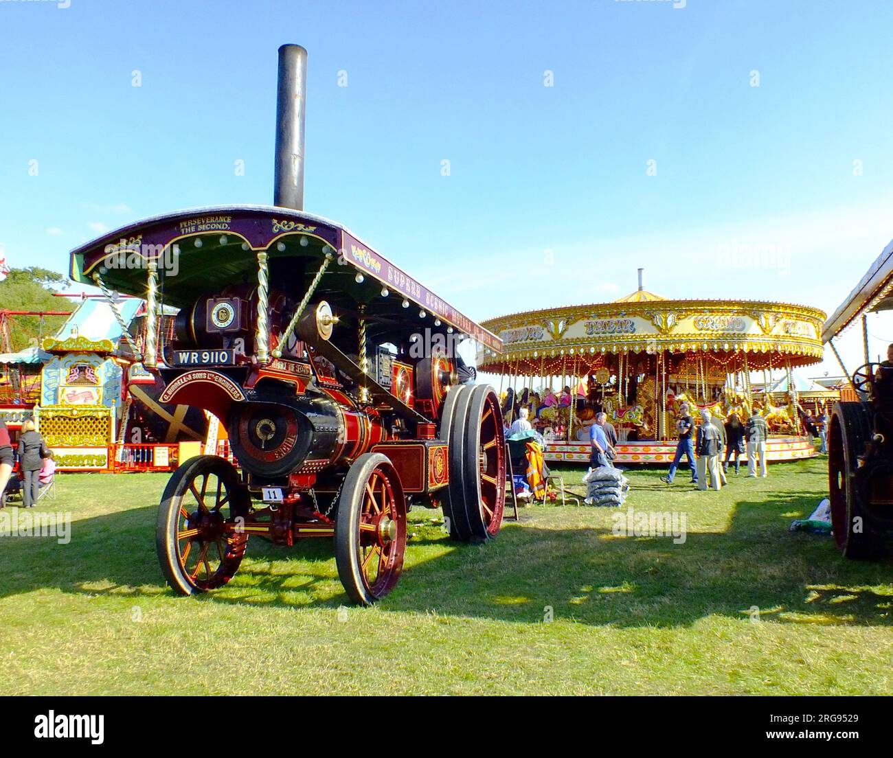 Welland Steam Fair, in der Nähe von Malvern, Worcestershire, mit allen möglichen Landwirtschaftsfahrzeugen und Messegeländemaschinen. Hier sehen Sie eine farbenfrohe Messegelände-Lokomotive mit einem Kreisverkehr im Hintergrund. Stockfoto