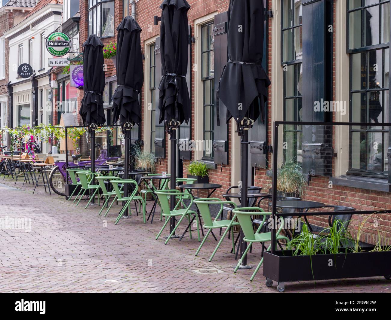 Stühle und Tische vor den Bars in der Krommestraat in der niederländischen Stadt Amersfoort, Niederlande, Europa. Stockfoto