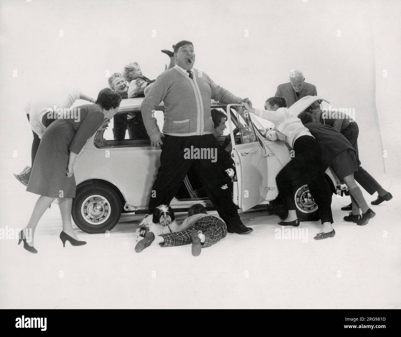 Werbung für CPV (Colman Prentis & Varley) – eine Gruppe von Personen (eine große Familie in verschiedenen Altersgruppen), die versuchen, sich in einen Austin (Mini) zu drängen (4/4). Stockfoto