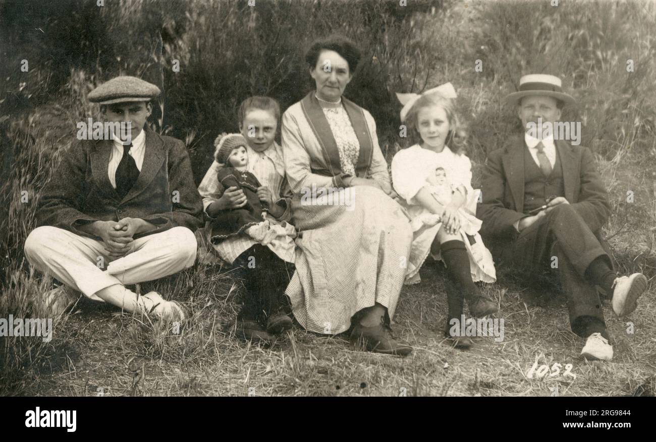 Die britische Familiengruppe posiert für ein Foto – die beiden jungen Töchter halten stolz ihre Lieblingspuppen in der Hand. Stockfoto