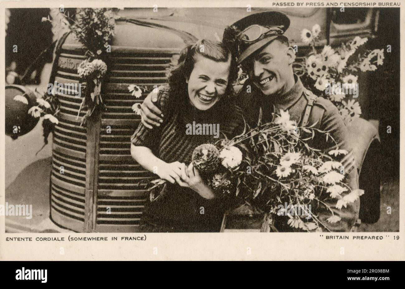WW2 - Entente Cordiale - irgendwo in Frankreich. Ein britischer Fahrer macht sich einen neuen Freund, der sich bereits selbst die Aufgabe genommen hat, seinen Lkw mit üppigen Girlanden voller Blumen zu dekorieren! Stockfoto