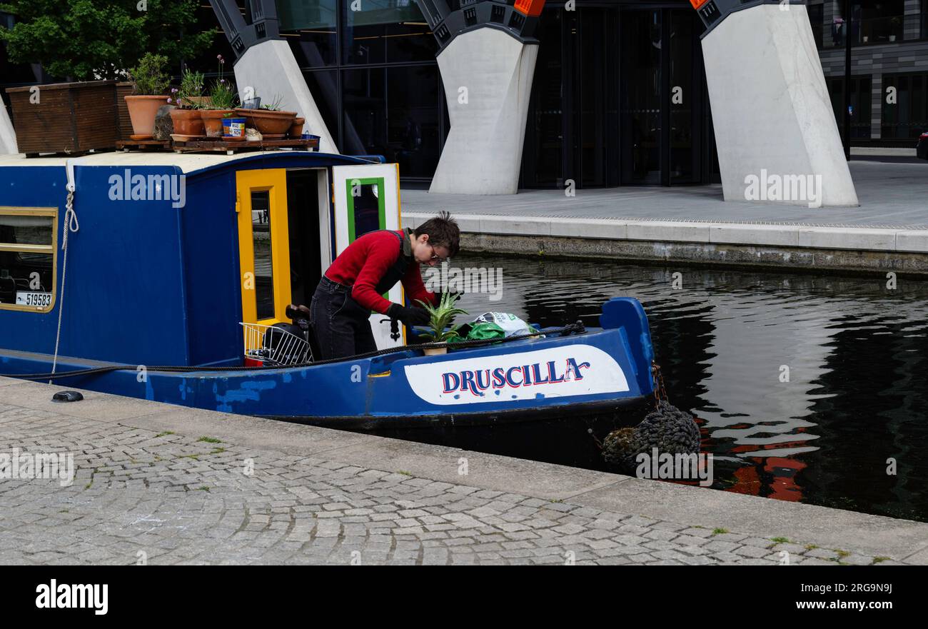 London - 05 29 2022: Frau pflegt ihre Pinatas auf ihrem Hausboot in Paddington Basin Stockfoto