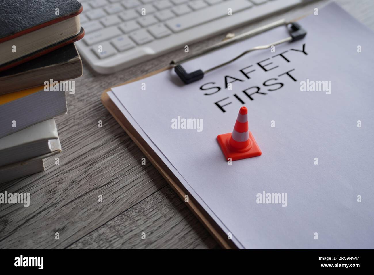 Nahaufnahme des Miniatur-Sicherheitskegels auf der Oberseite des Papierclipboards mit dem Text SAFETY FIRST. Stockfoto