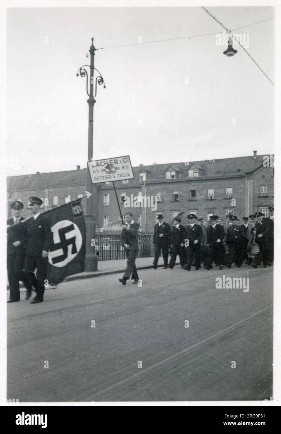 Rallye - Parade - Pforzheim, Südwestdeutschland am 1. Mai 1935. Unter der Flagge der Nazis stehen Arbeiter von LACO (Lacher & Co), die im Jahr WW2 Uhren für deutsche Airforce-Piloten und Beobachter von Bombenflugzeugen herstellten. Stockfoto