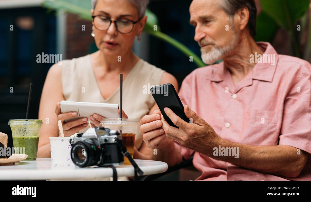 Zwei ältere Menschen, die ihr Smartphone in der Hand halten und reden Stockfoto