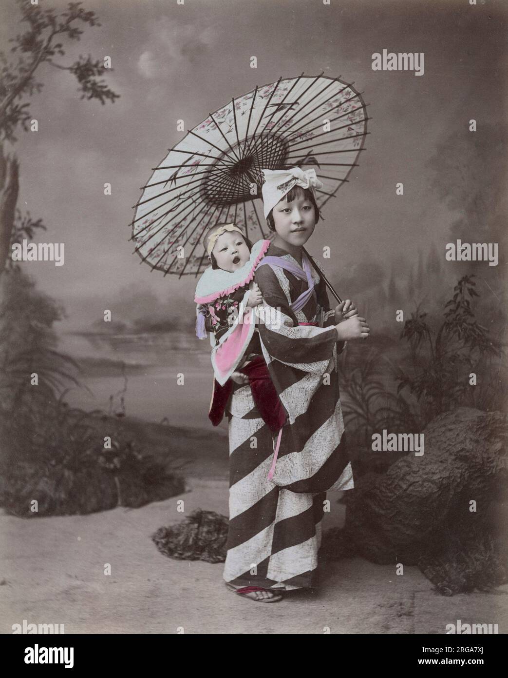 Junge Frau oder Krankenschwester / Kindermädchen, die ein Baby trägt, Japan. Vintage 19. Jahrhundert Foto. Stockfoto
