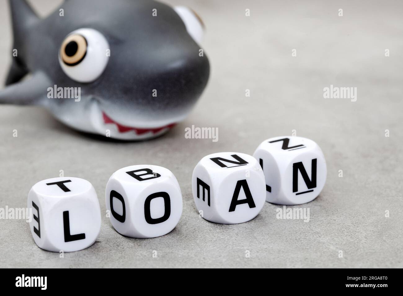 Einsame Haie. Das Wort Loan mit Spielzeughai auf Grau Stockfoto