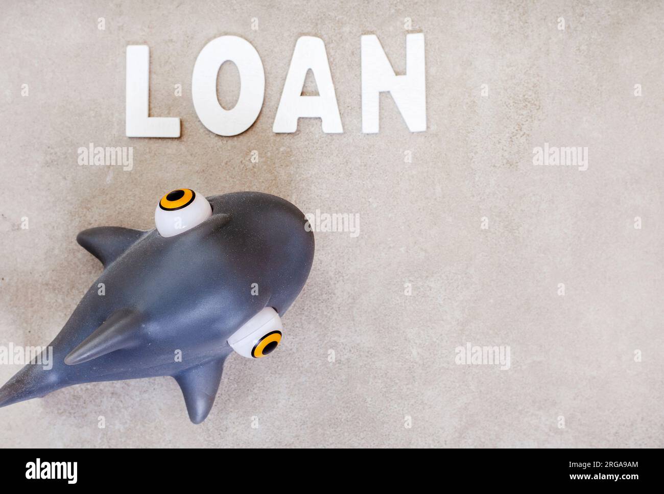 Einsame Haie. Das Wort Loan mit Spielzeughai auf Grau Stockfoto