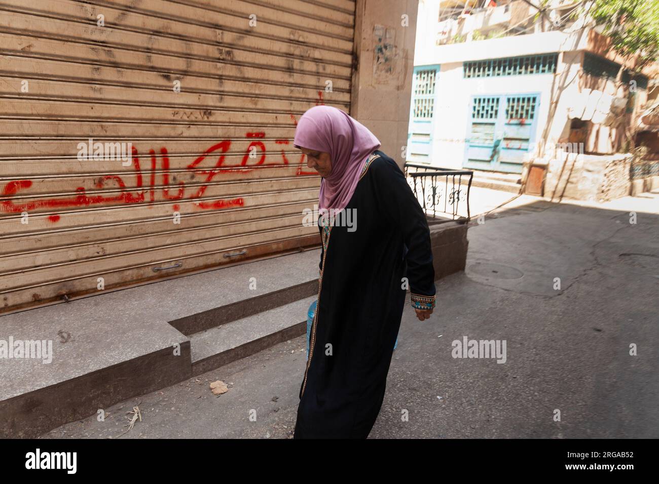 BEIRUTE, BE - 11.07.2023: LIBANESISCHES FLÜCHTLINGSLAGER - Eine Frau läuft mit einer 8-Liter-Flasche Wasser in den Straßen des Shatila-Flüchtlingslagers. Beirut - Libanon (Foto: Nicolò Ongaro/Fotoarena) Stockfoto