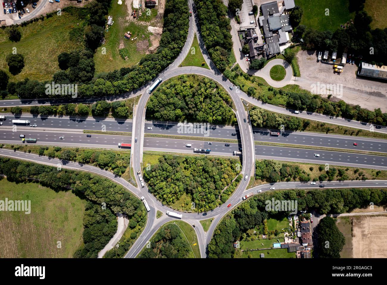 Luftaufnahme direkt über einer geschäftigen Straßenkreuzung auf einer britischen Autobahn mit Überbrückung und Zufahrtsstraßen in der britischen Landschaft Stockfoto