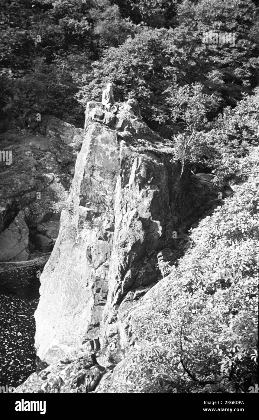 Schottische Hügel und Seen: - Schottischer Gentleman, der auf einem Felsen ruht, über einem Gebirgskuchen Stockfoto