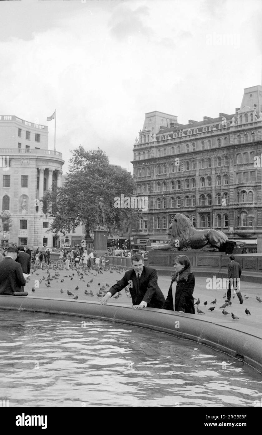 Trafalgar Square: Ein Paar, das einen Brunnen genießt, mit einem Wächter Löwe und der Statue von Generalmajor Sir Henry Havelock im Hintergrund. Stockfoto