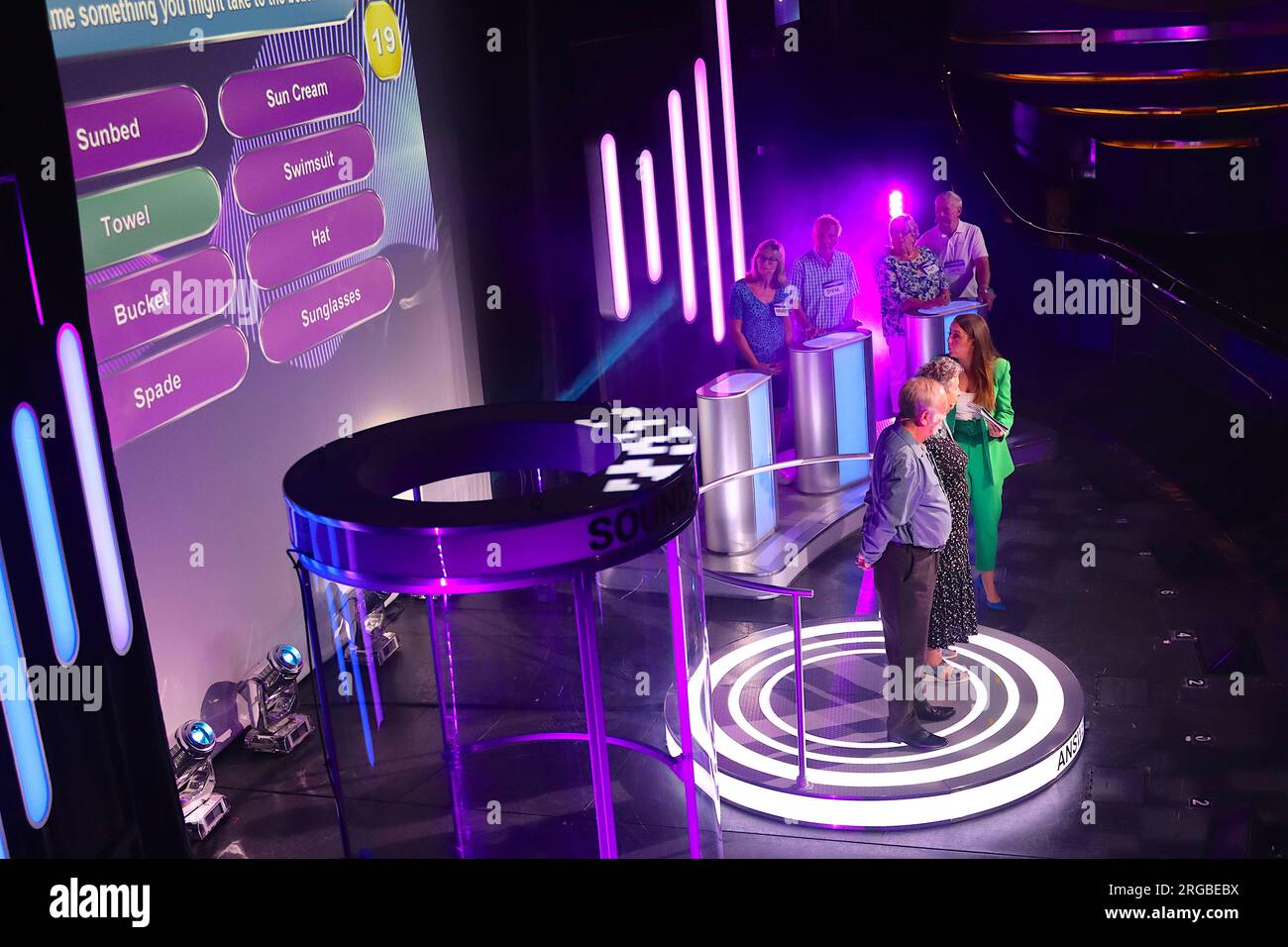 Die Teilnehmer Yvonne & John auf einem Podest erhalten die gleiche Frage, die sie den anderen Paaren stellen, um zu sehen, wie viele ihrer Antworten mit ihren Antworten übereinstimmen. Stockfoto