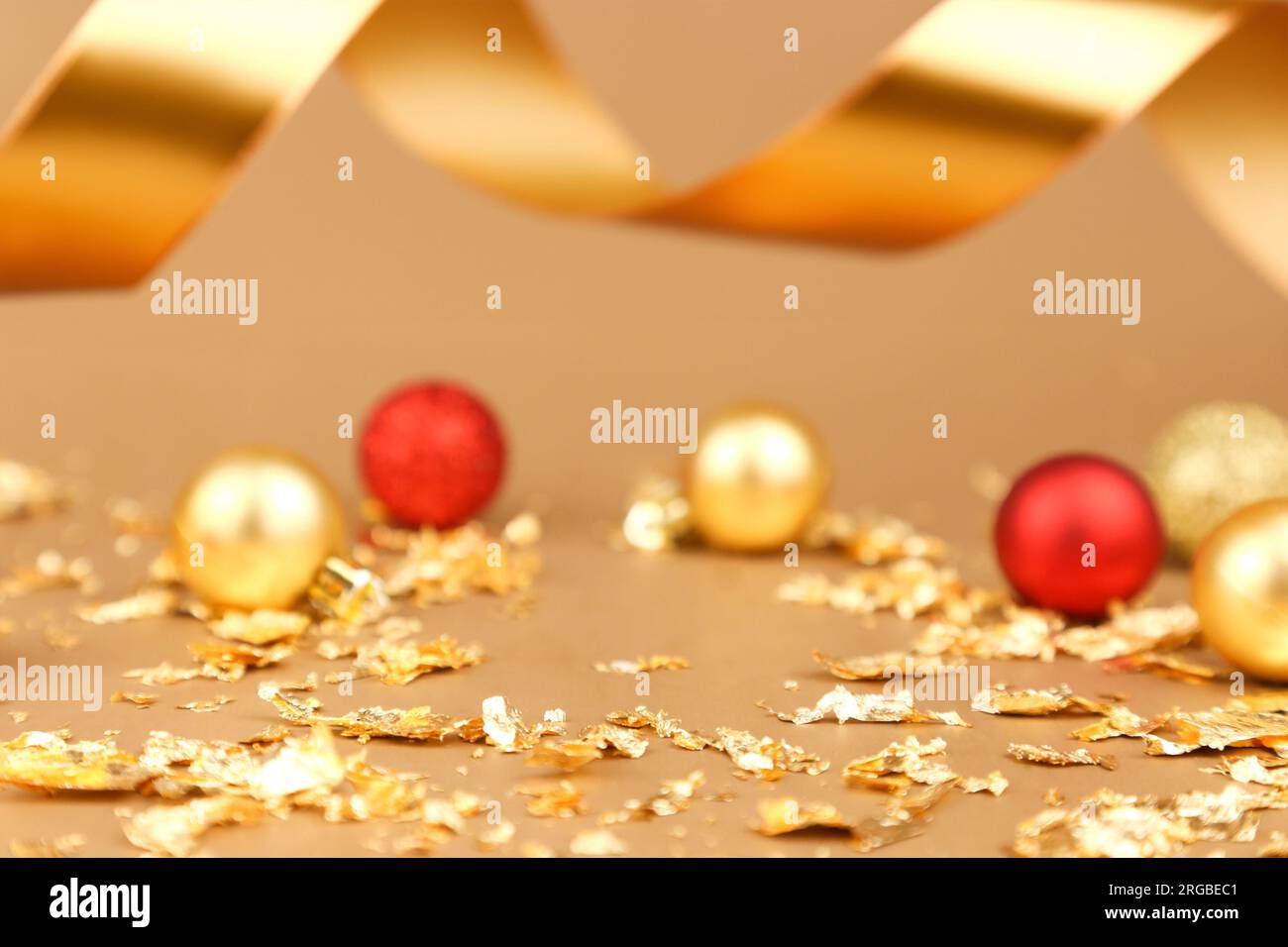Hintergrund für Produktwerbung. Rote goldene weihnachtskugeln, goldene Papierknallstücke, goldenes Band auf goldenem Hintergrund. Freier Platz Stockfoto