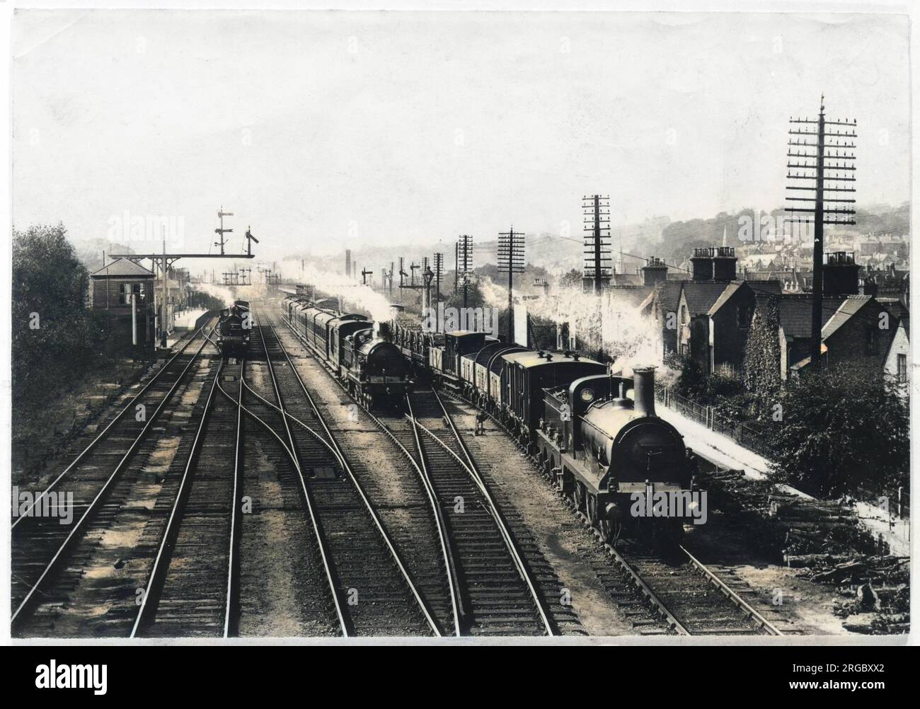 Ein Güterzug wartet auf einem Gleis, um den Personenzug durchfahren zu lassen, während ein dritter Zug durch den Bahnhof in Redhill, Surrey, fährt. Stockfoto