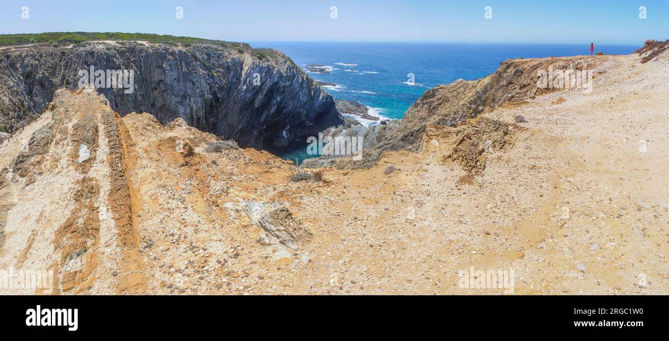 Weibliche Besucherin, die die Klippen der Küste von Cabo Sardao, Ponta do Cavaleiro, Sao Teotonio, Portugal betrachtet Stockfoto