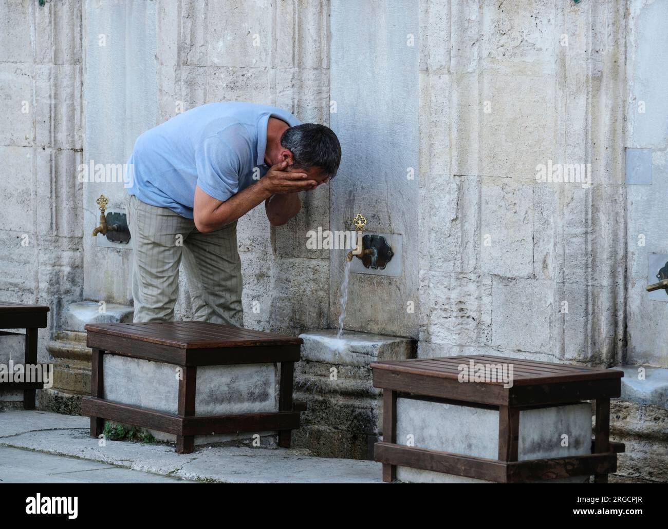 Istanbul, Türkei, Turkiye. Ein Mann, der vor dem Betreten der Suleyman-Moschee, der herrlichen Suleymaniye-Moschee, Abwässer vorführt. Stockfoto