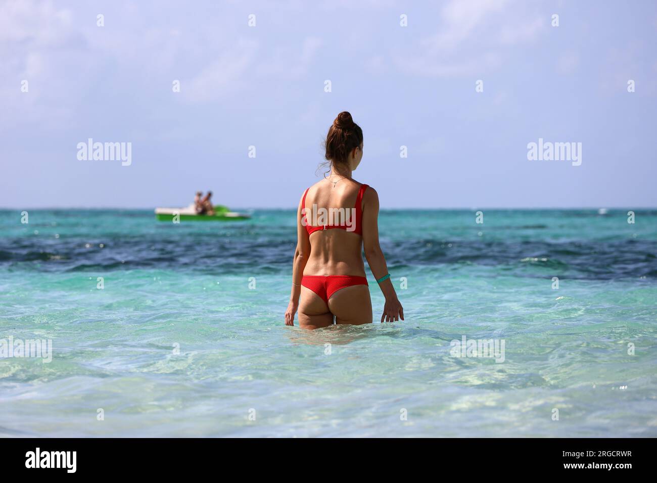 Schlankes Mädchen in rotem Bikini, das im blauen Meerwasser schwimmen geht. Strandurlaub an der tropischen Küste Stockfoto