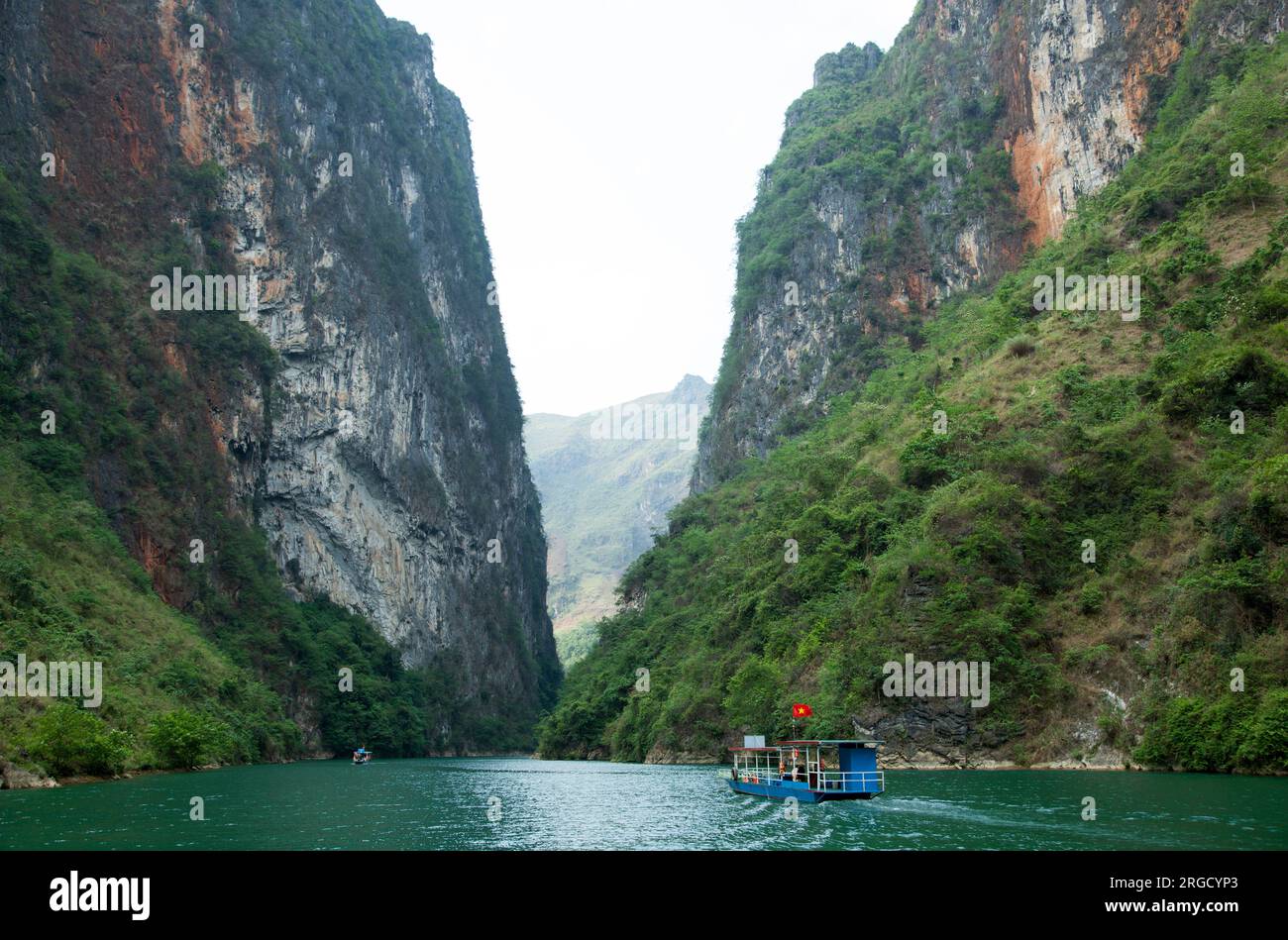 Der malerische Blick auf einen tiefen Canyon und Touristenboote, die entlang des Nho Que River (Vietnam) fahren. Stockfoto